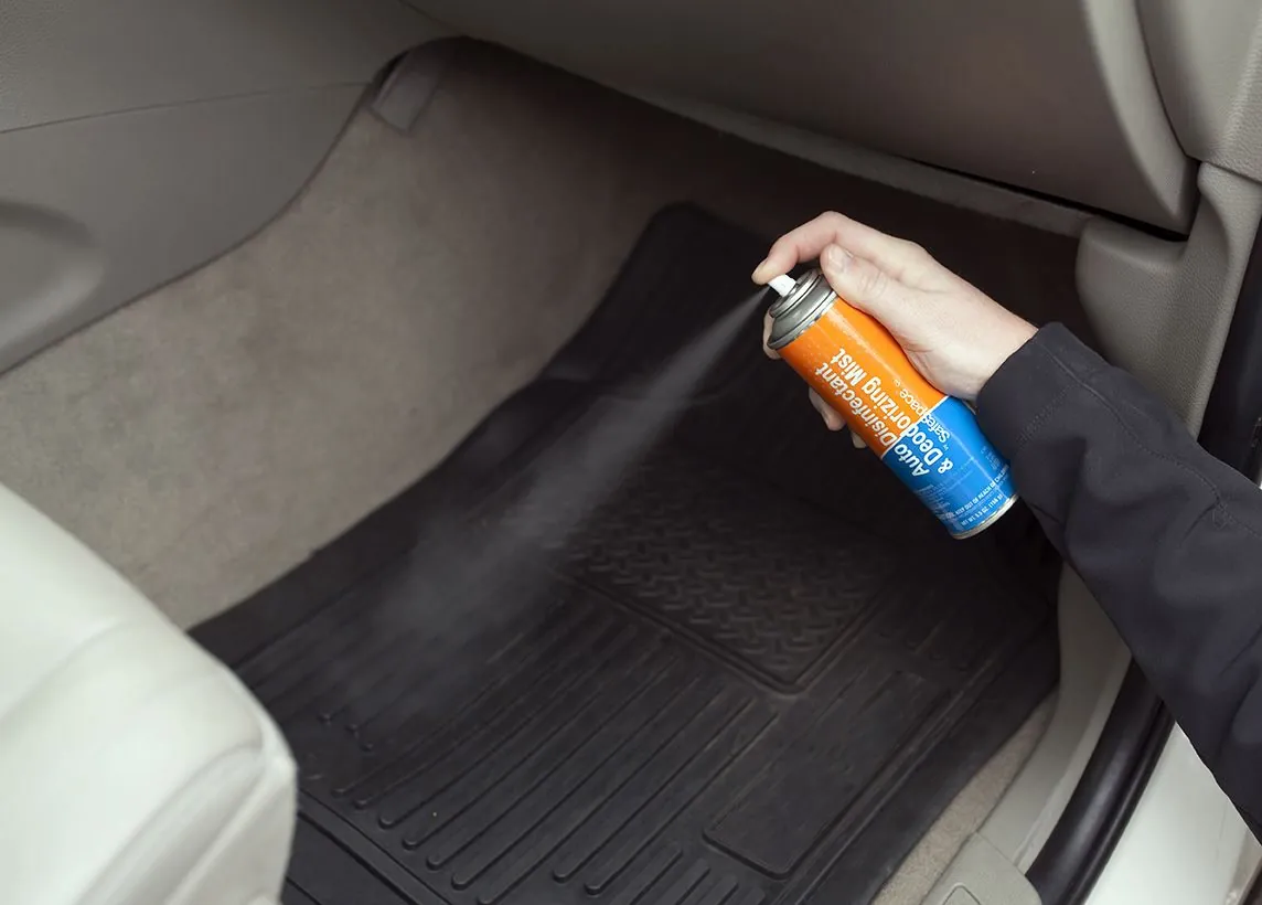 Aerosol limpiador sobre el tapete del piso del auto