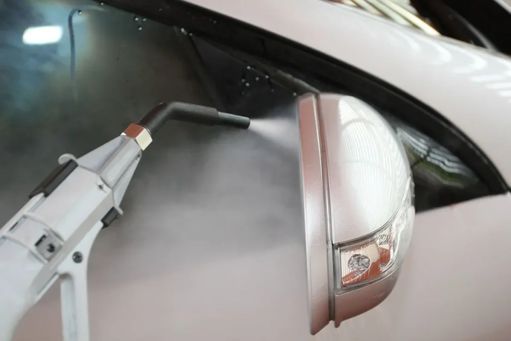 Boquilla de vapor limpiando el espejo lateral de un auto