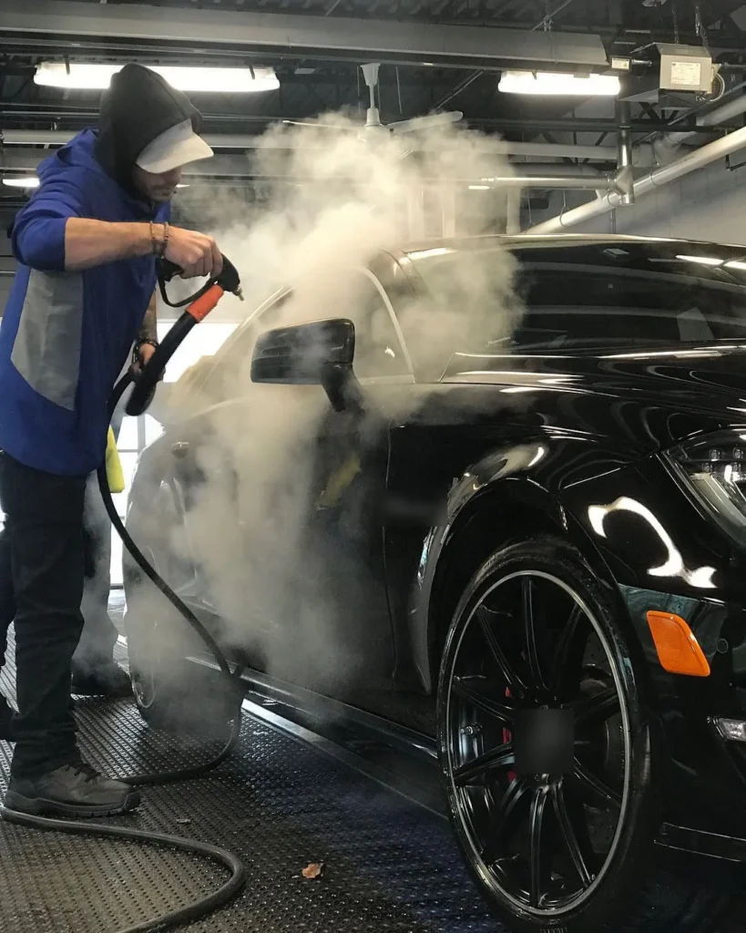 Lavado con vapor de un auto negro dentro de un garaje