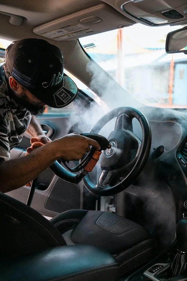 Limpieza con vapor del volante y la cabina, operario con cubrebocas