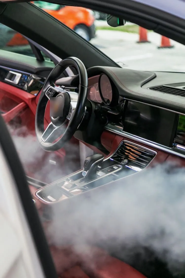 Nube de vapor sobre la consola de un auto con interior rojo: limpiar techo de auto con vapor